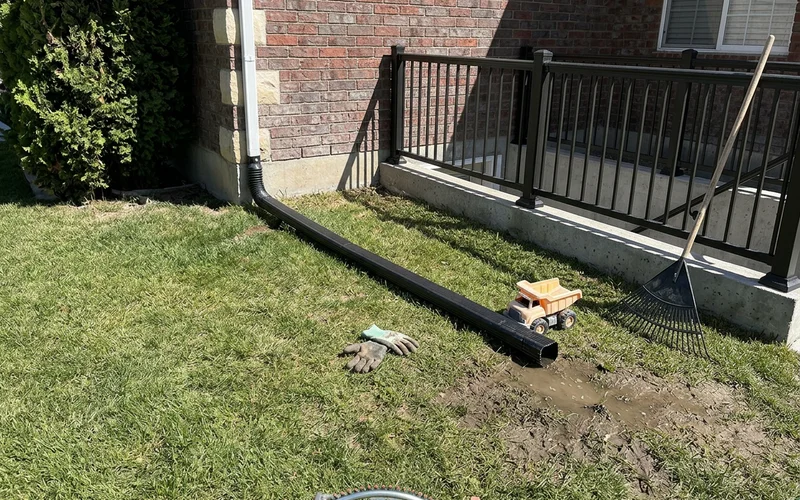 Downspout extension directing roof water away from a walkout