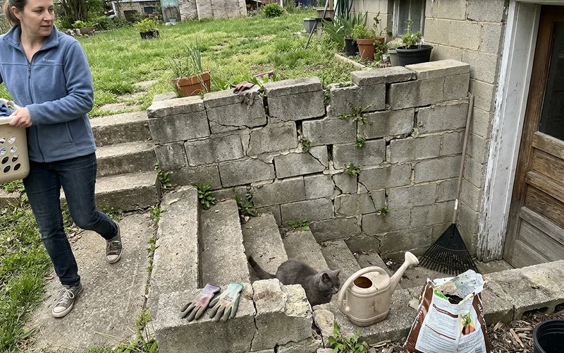 Old cracked and leaning block wall beside worn walkout steps