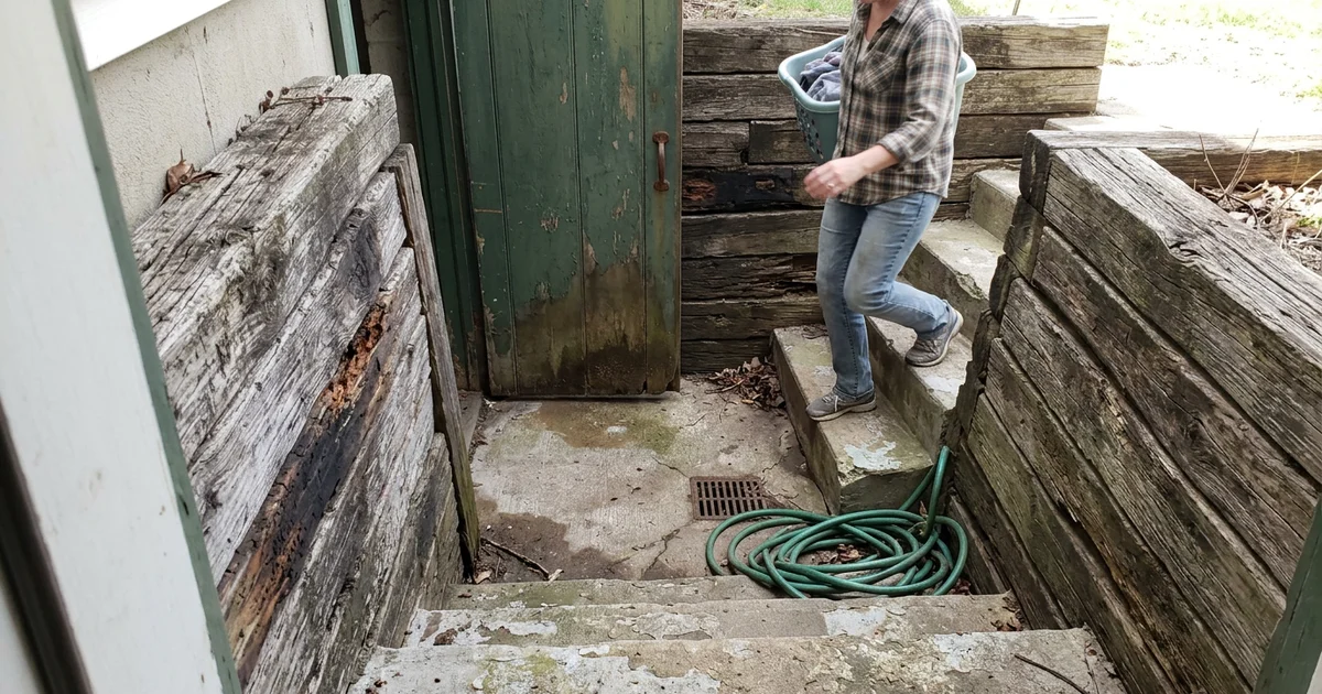Old basement walkout with rotting railroad tie walls and worn steps