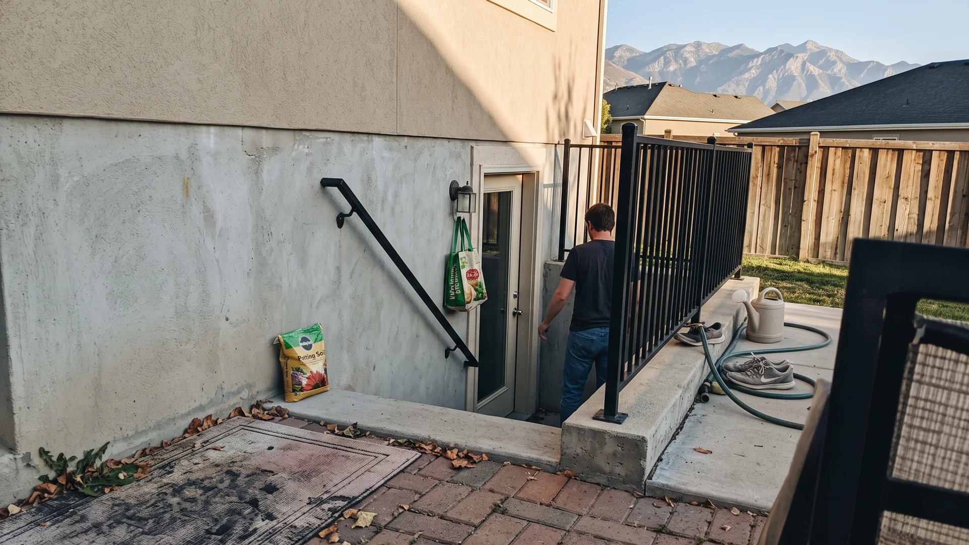 Illustration of a finished concrete basement walkout with railing and door behind a Utah home
