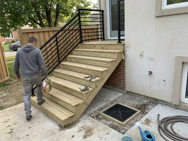 Illustration of rebuilt walkout stairs with a landing, railing and catch basin